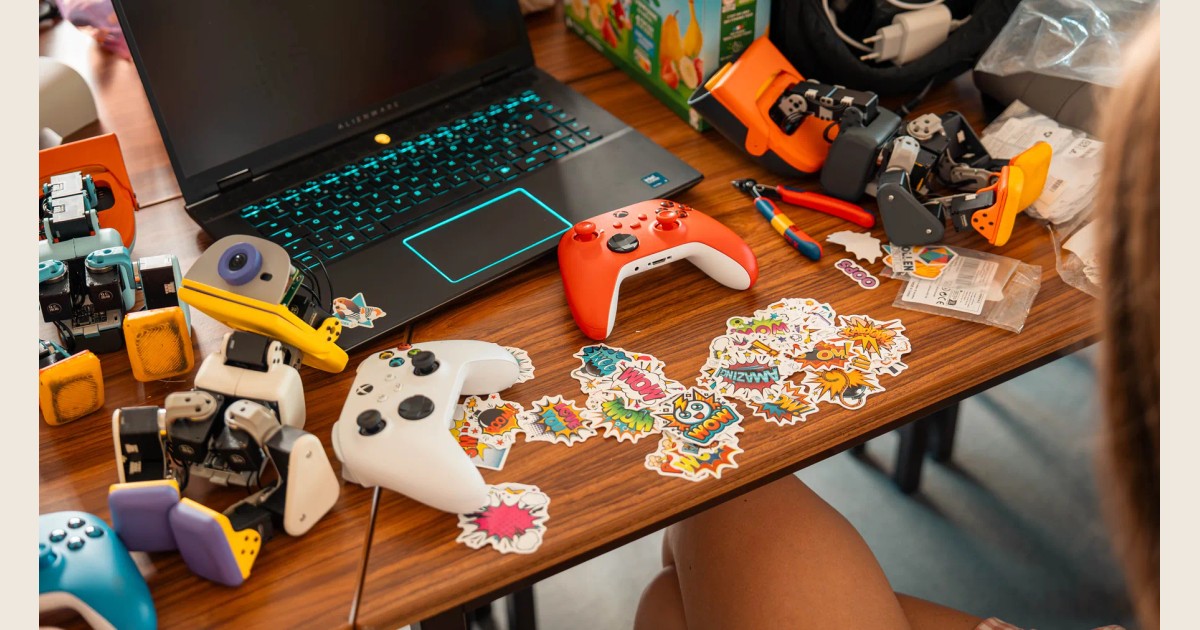 Fotografía oficial de varios Microduck sobre una mesa de trabajo, junto a un portátil, mandos de videojuegos, herramientas y pegatinas.